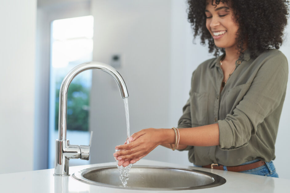 woman washing her hands at the kitchen sink