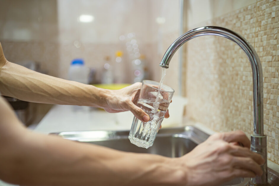 person filling a glass with tap water