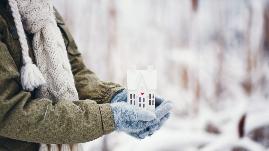 hands holding tiny home in snowy weather