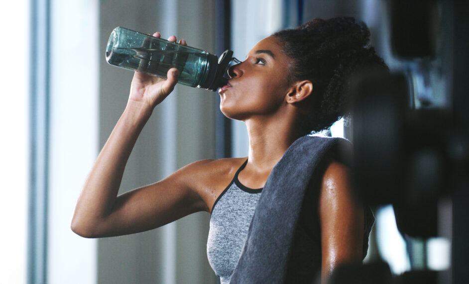 young woman drinking water at the gym